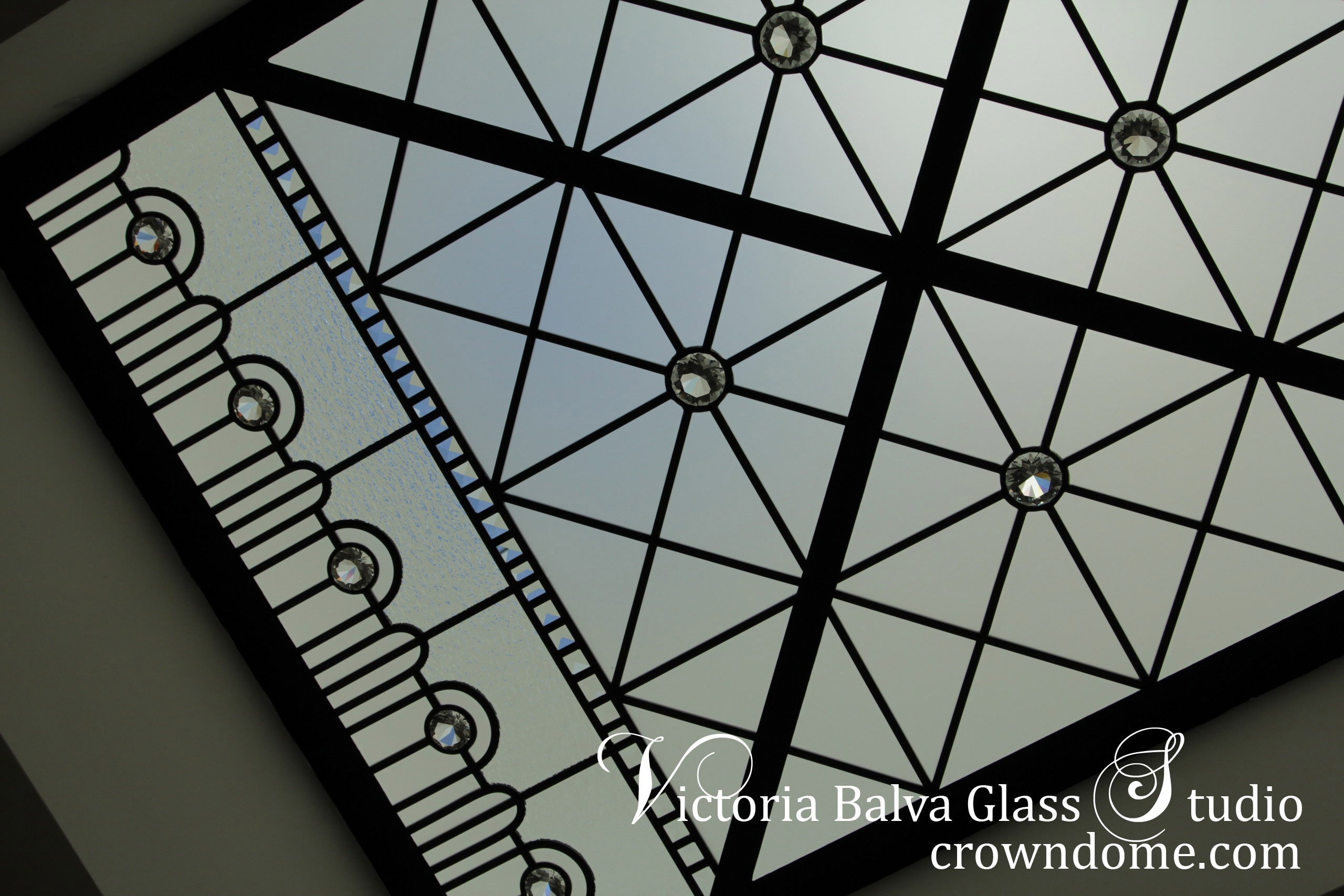 Beautiful geometric stained leaded glass skylight ceiling for a hallway of a luxury custom built residence with clear textured glasses, beveled glass and clear crystal jewels as accents. The contemporary styling of the glass ceiling design brings modern feeling into space with a reference to a classic design reflecting a modern lifestyle of the residents. Leaded glass skylight design by stained glass artist Victoria Balva