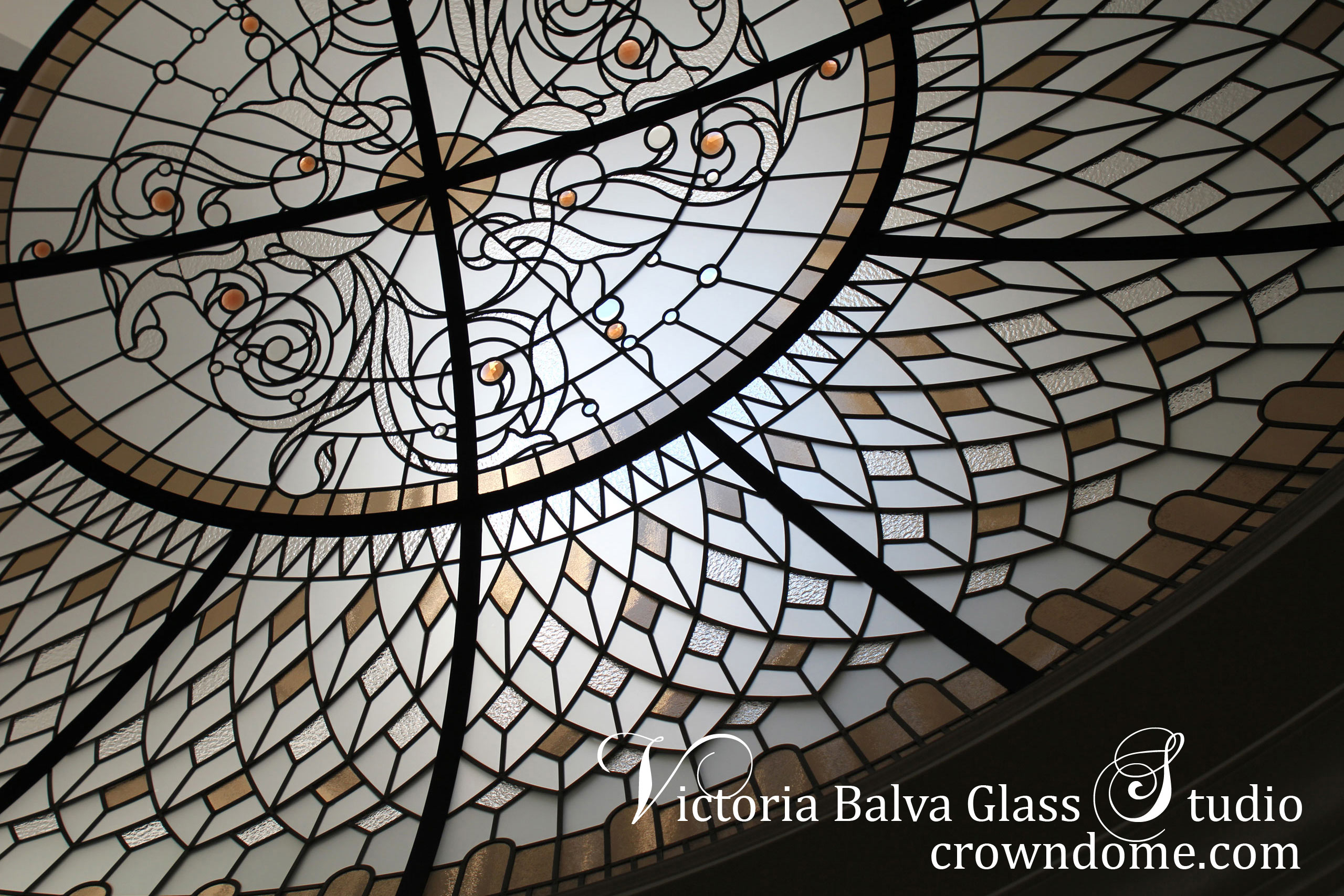 Oval stained leaded glass dome skylight ceiling with rosette ornament for an oval hallway of a custom built house. Large oval stained leaded glass dome skylight ceiling masterpiece with bronze textured glass and colored jewels.