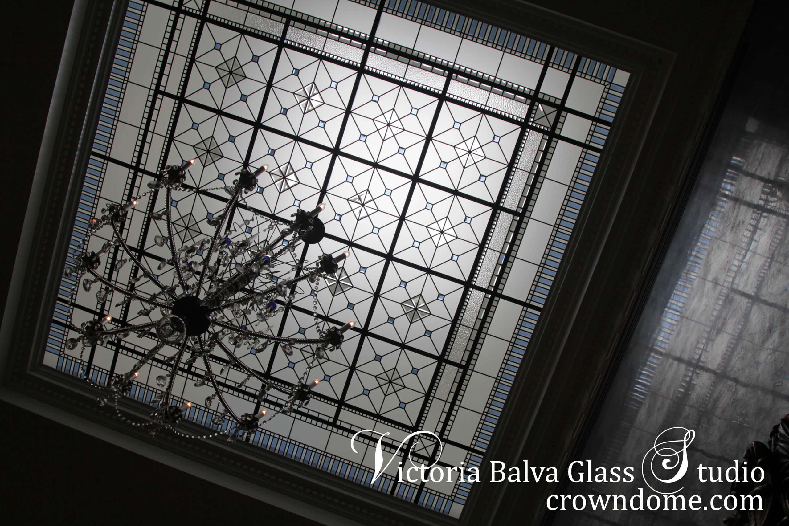 Large leaded glass skylight for a double height grand entrance foyer of a custom built residence inspired by historical Greight Britain estates. Large crystal chandelier with blue accents suspended from a center of the decorative glass ceiling