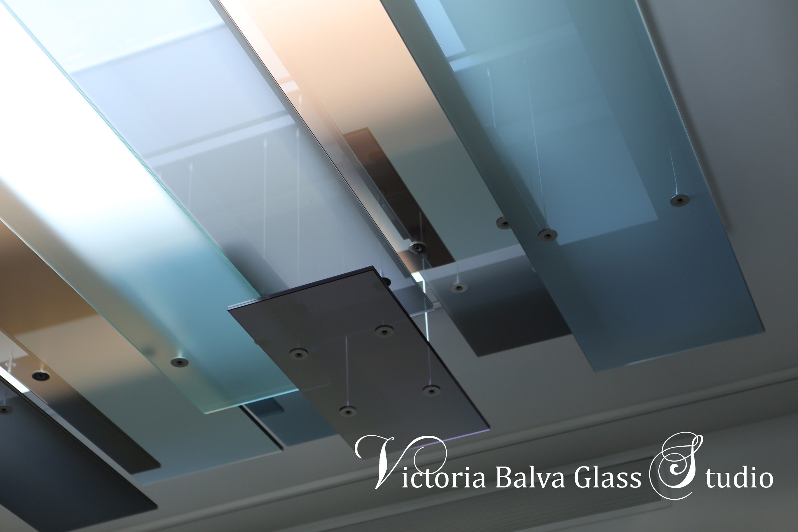 Minimalism style art glass skylight installation for foyer of large modern residence Laminated reflective textured colored glass with polished glass edge suspended on stainless steel hardware and steel cables for contemporary residence in Toronto