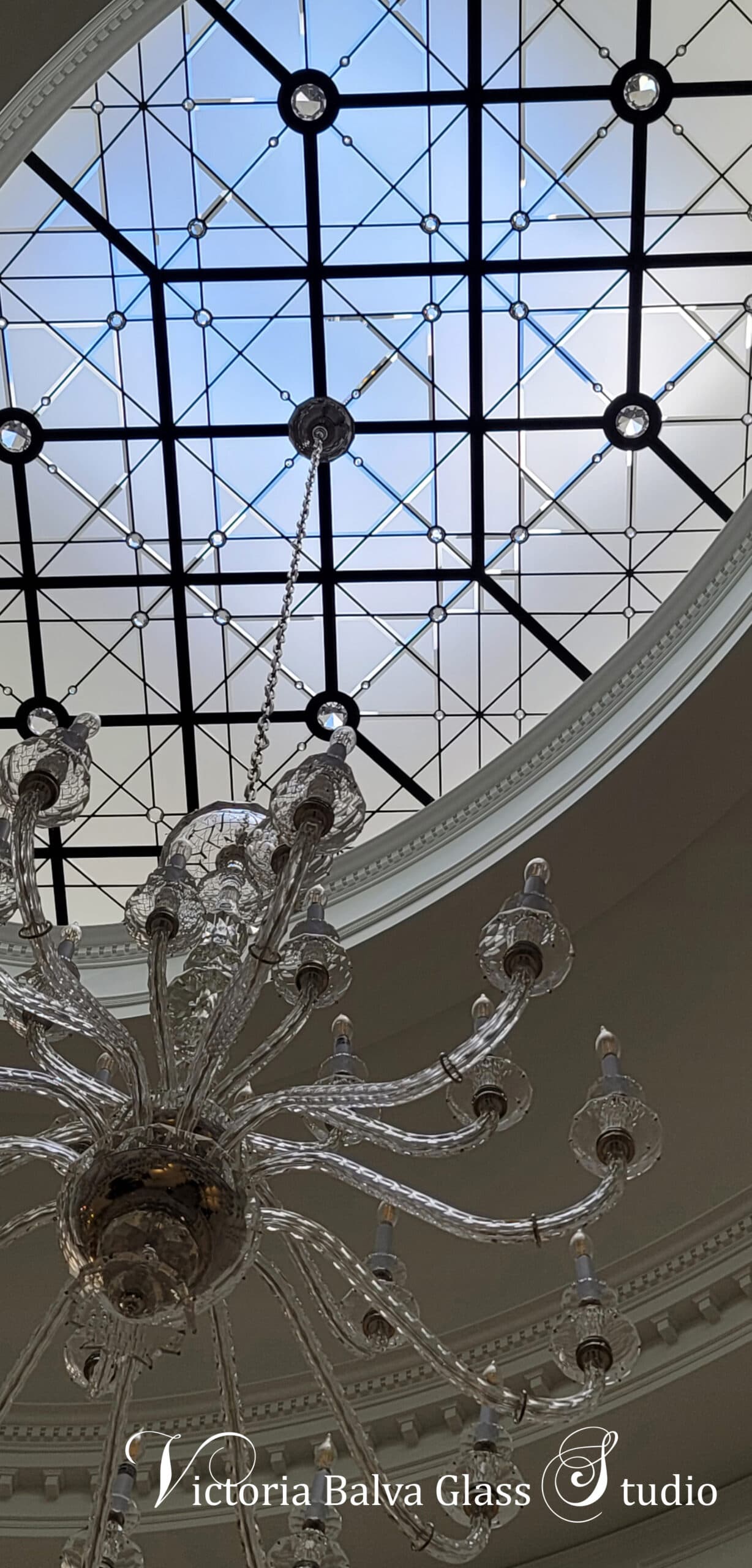 Large crystal chandelier in the oval double height entrance foyer with a stained and leaded glass skylights